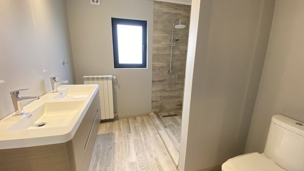Baño con doble lavamanos y ducha revestida en cerámica símil madera