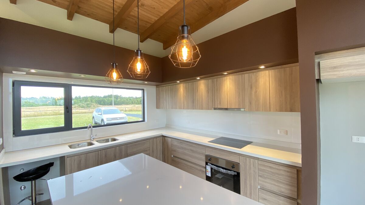 Cocina con isla, vigas de madera y ventana al campo