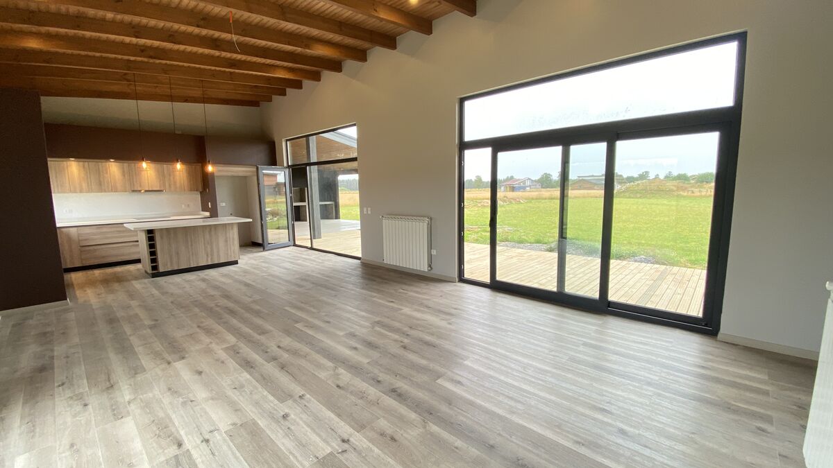 Living y cocina con ventanales y piso de madera