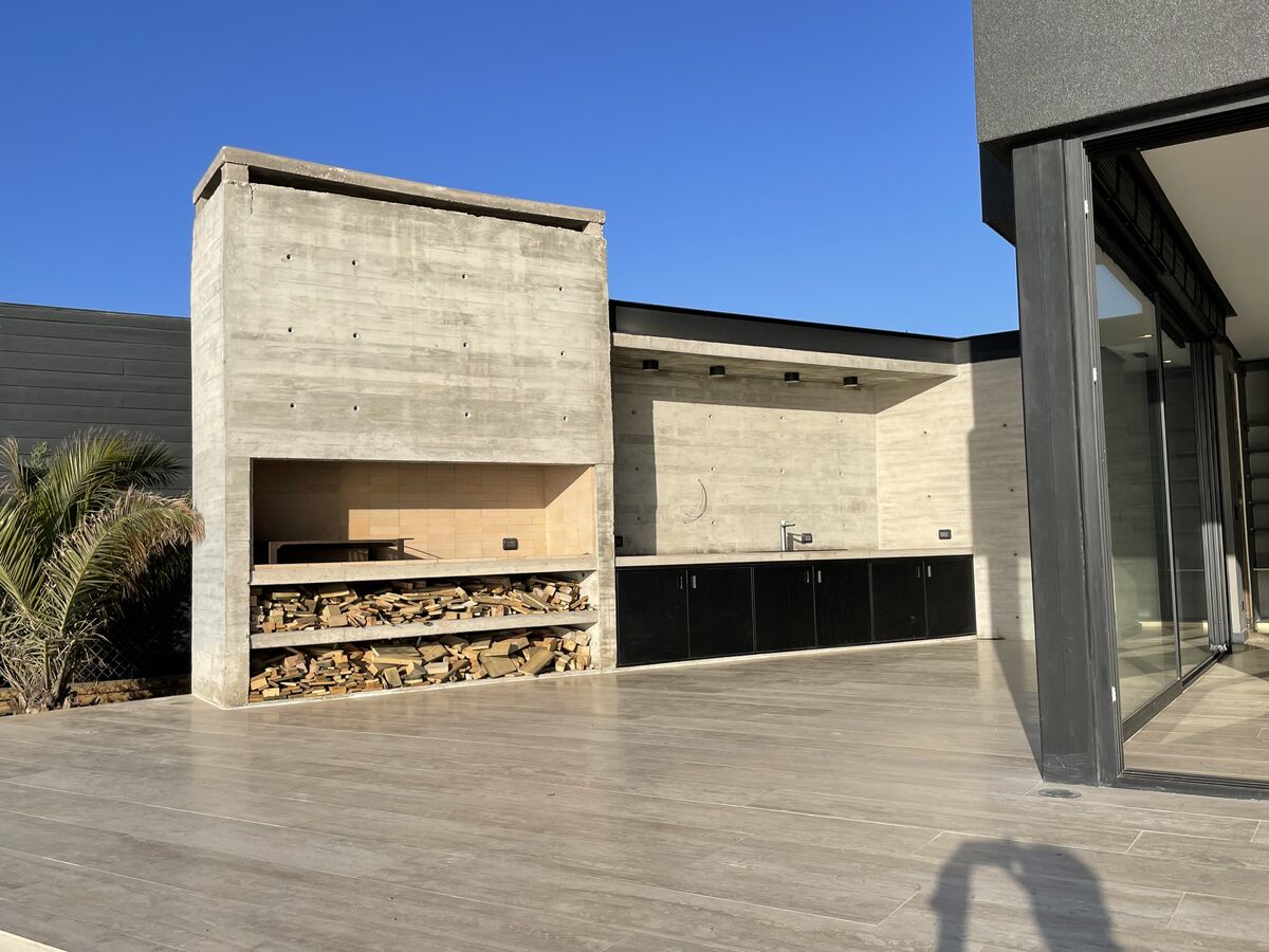 Quincho de hormigón con leñera y terraza